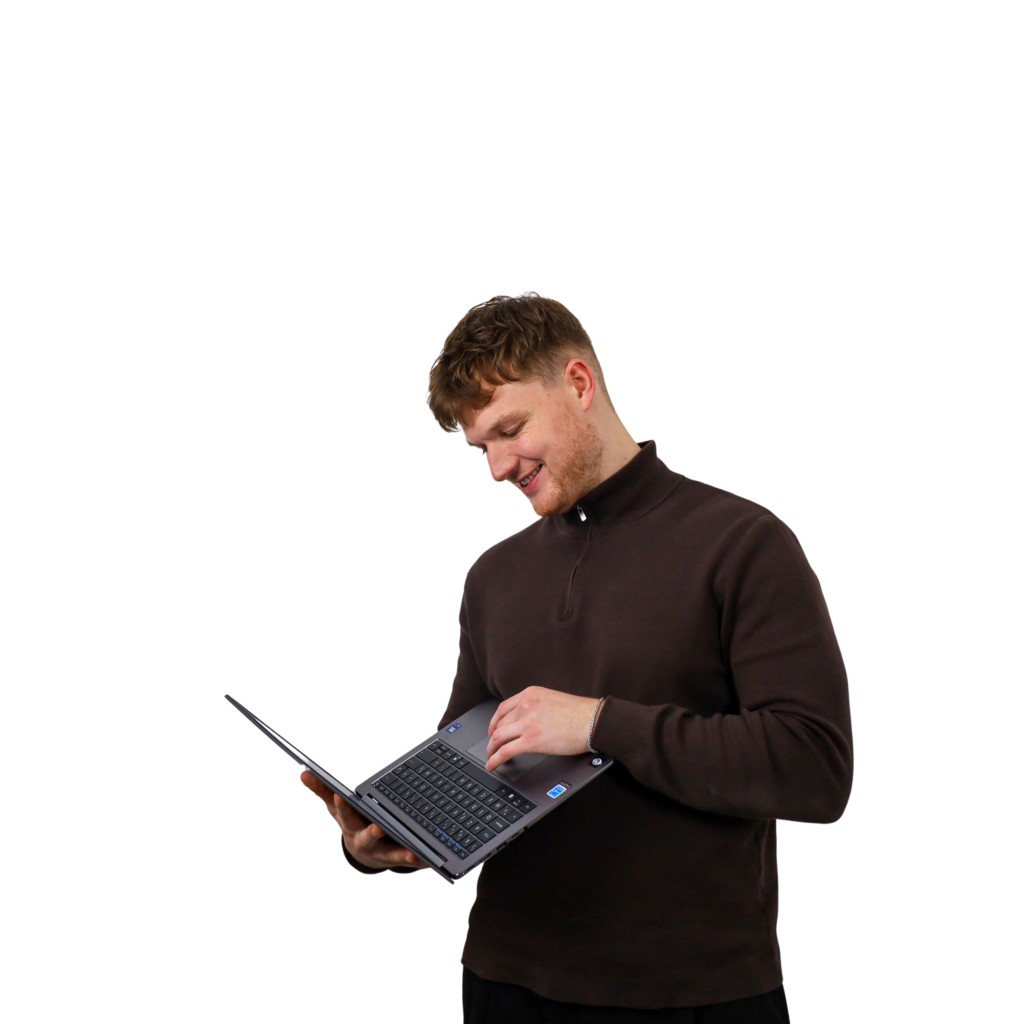 Een man met een donkere trui die op zijn laptop aan het werken is.